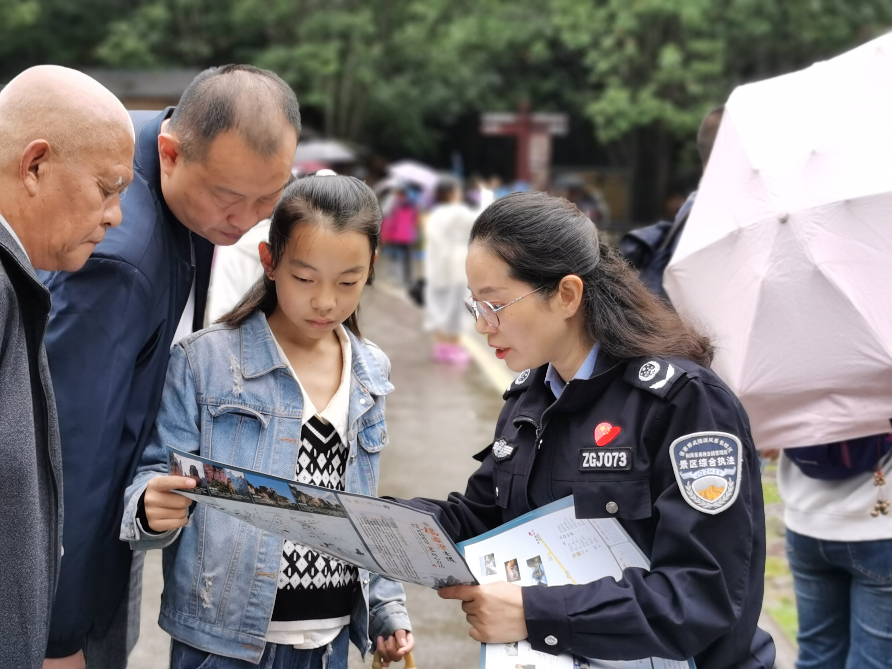 10月1日上年，金鞭溪景區(qū)管委會女子執(zhí)法隊隊員開展流動導(dǎo)覽服務(wù)，為游客免費贈送地圖。張娜 攝